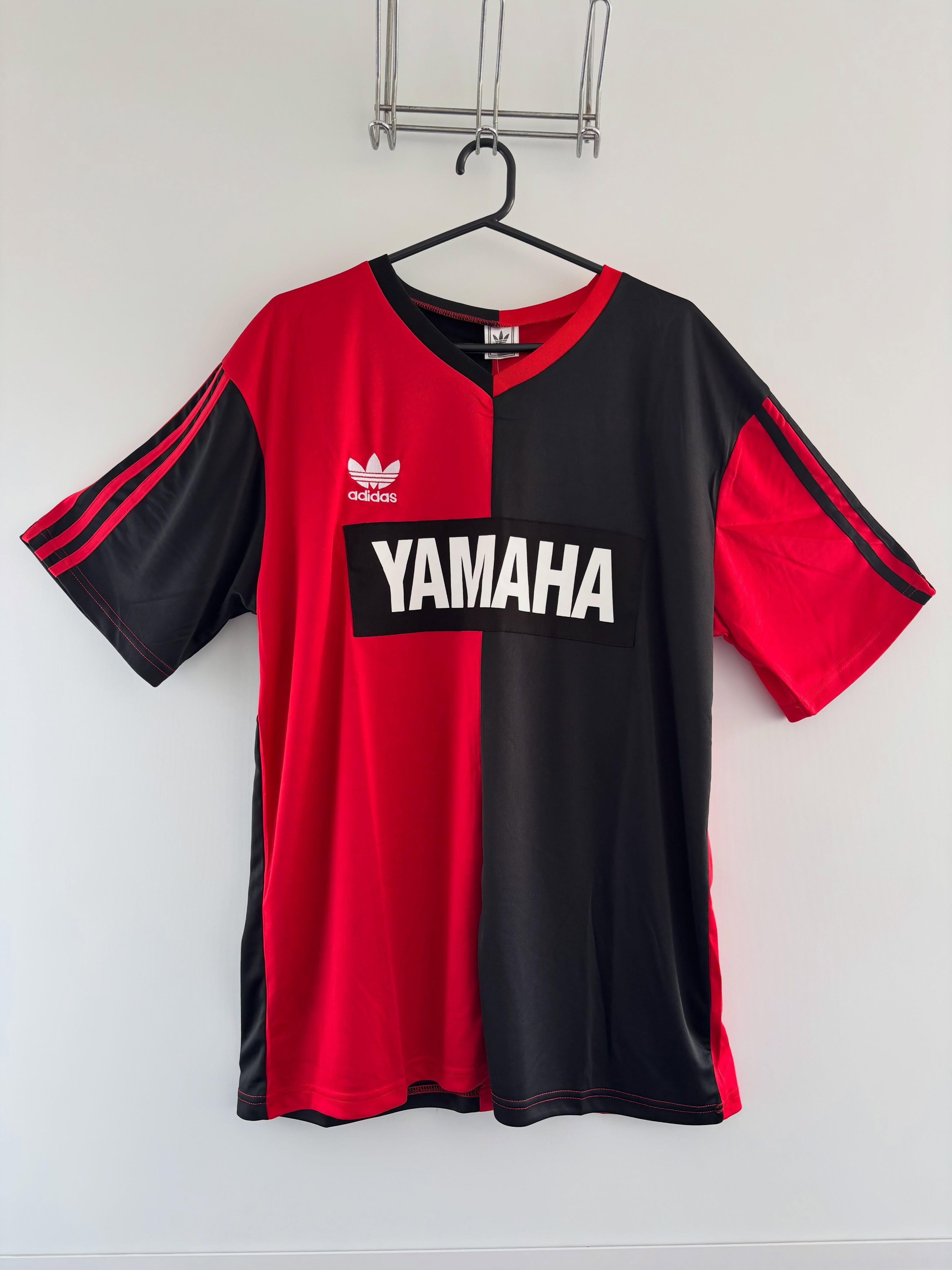 Camiseta Newell's 1993, roja y negra, colgada en una percha